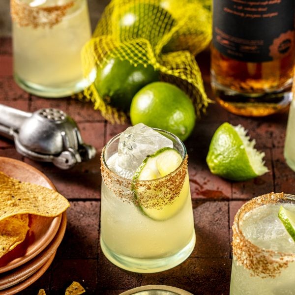 A margarita surrounded by limes and cocktail accoutrements