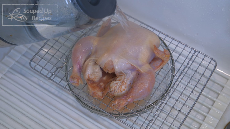 Image of Bring the Cornish hen to the sink with a rack under it. Boil some water using an electric kettle and pour it all over the chicken. The heat will stretch the skin and make it nice and smooth. Don’t worry...