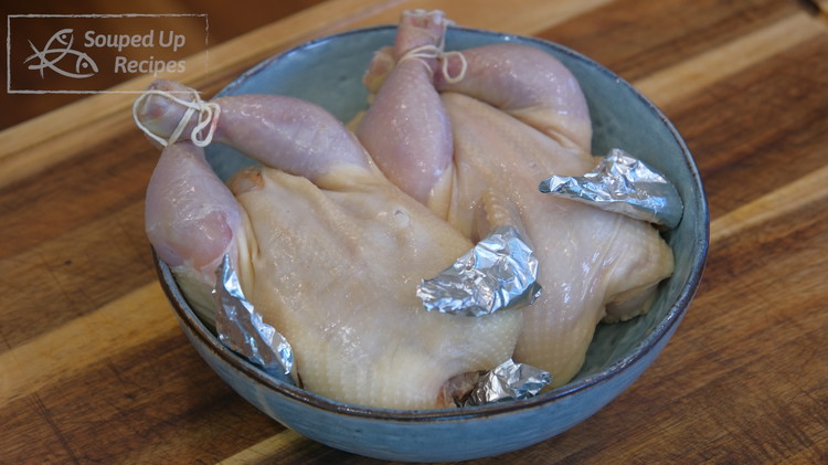 Image of Tie the chicken leg with kitchen twine and wrap the wing tip with tin foil so it doesn’t burn.