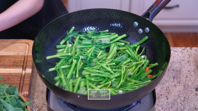 Image of Here is the water stir fry trick. Pour in 1/4 cup of hot water and add the water spinach stems, garlic, and Thai bird eye chilies at the same time. All these ingredients calm the splash. Under high temperatures, the...