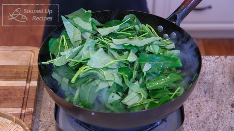 Image of Add the stir fry sauce and water spinach leaves. Keep mixing until the leaves are wilted.