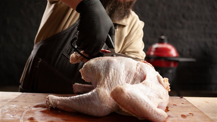 Image of Spatchcock the turkey by using poultry shears to cut all...