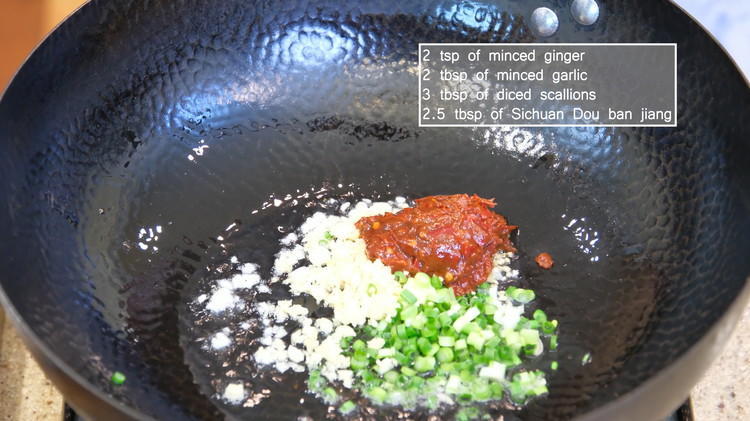 Image of To the same wok, add oil, minced ginger, garlic, diced scallions, and Sichuan Dou ban jiang, and stir over medium-low heat for a few minutes or until everything becomes bright red.
