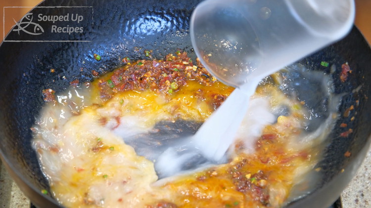 Image of Pour the starch water into the wok. Bring it to a simmer and stir until the soup is slightly thickened.