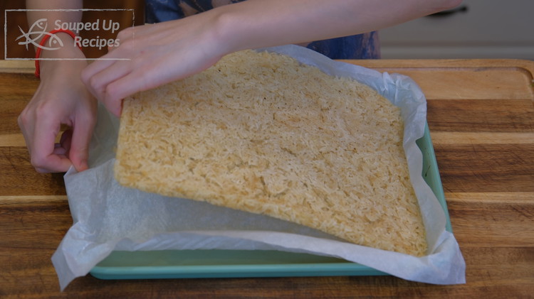Image of This is how the rice looks when you take it out of the oven. It is fully dried and hard. Remove the parchment paper and you can break the rice into bite-size pieces.