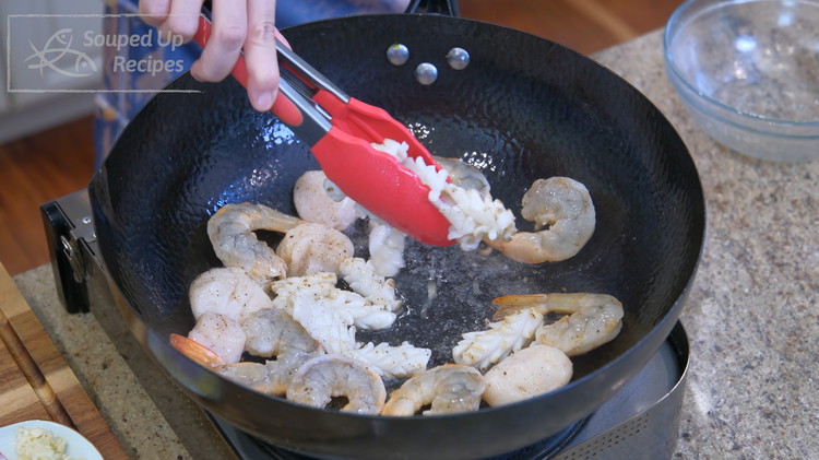 Image of Turn the heat to high. Add a drizzle of oil. Sear the seafood until golden brown. The squid cooks fast, so you have to take it out of the wok as soon as it curls. Set the seafood aside.