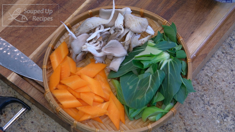 Image of For the vegetables, peel and slice a carrot into slices, slice a few pieces of bok choy into bite-size pieces, and tear the mushroom into bite-size pieces as well.