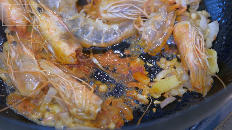 Image of To the same wok, add another drizzle of oil and toss in the shrimp heads, shells, garlic, ginger, and shallots. Stir for a few minutes or until the shrimp heads turn pink. You want to see some orange goodness rendering...
