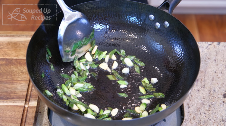 Image of Add a generous amount of cooking oil to a wok, along with the scallions and garlic slices. Stir over medium-low heat until the aromatics are golden brown.