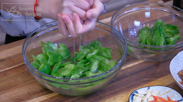 Image of Squeeze the excess moisture out of the bitter melon. Rinse off the salt with cold running water several times and drain thoroughly.