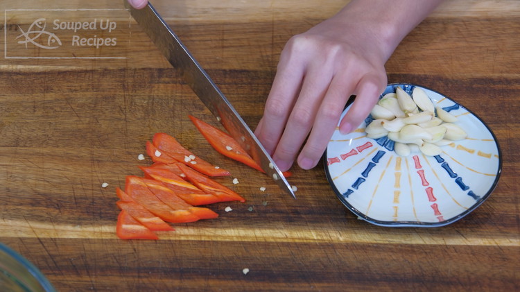 Image of While waiting, slice a few cloves of garlic thinly and cut a red chili into small pieces. If you don't eat spicy food, use bell peppers.