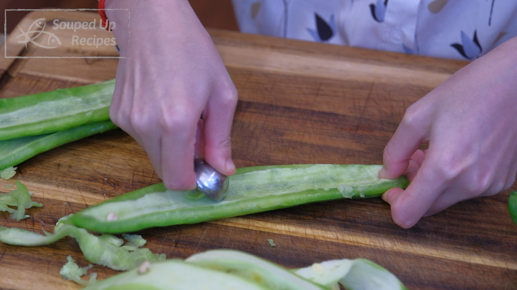 Image of Quarter the bitter melon lengthwise. Remove the white spongy part with a knife first, then scrape completely with a rounded teaspoon.