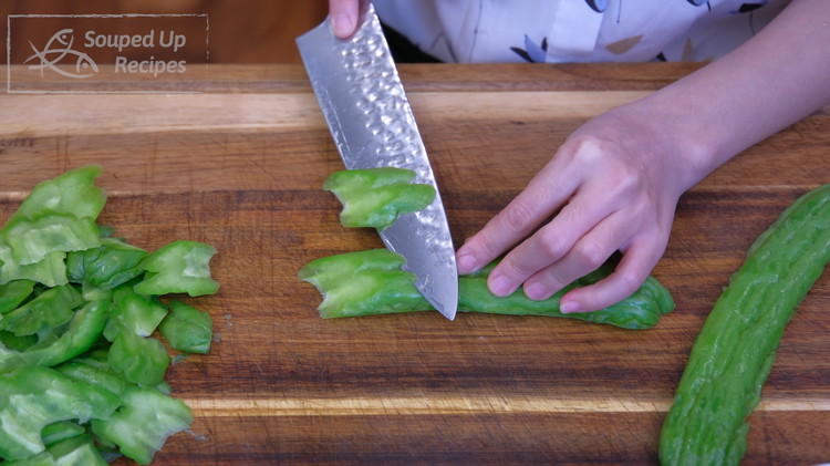 Image of Cut the bitter melon with a 45-degree angle into 1/3 of an inch thick slices.