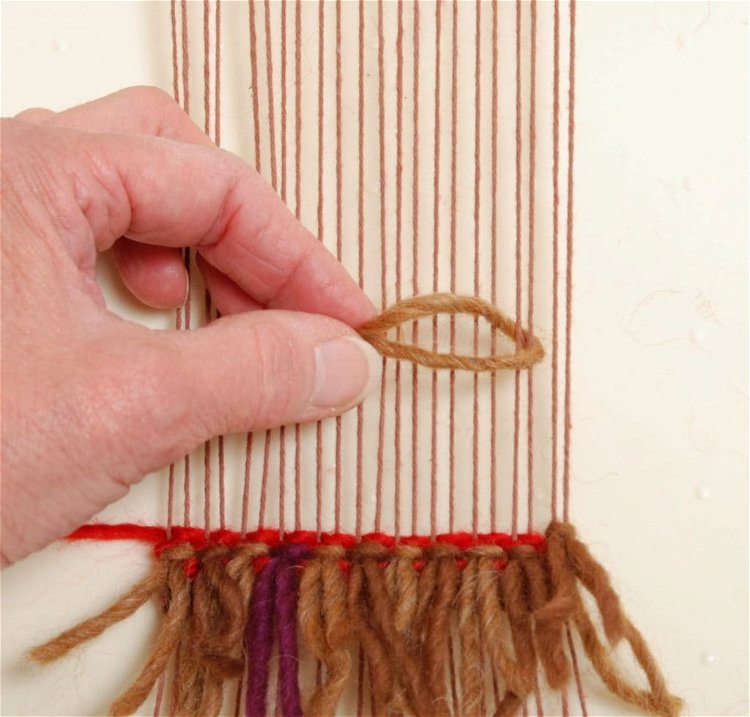 Image of Place a length of cut yarn around two warp threads....
