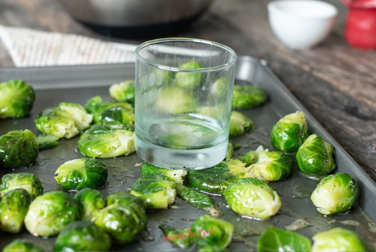 Image of Take two backing sheets and either line them with parchment or spray with nonstick spray. Place ½ of the Brussels on each sheet. Using the bottom of a flat glass or coffee cup, gently smash each Brussel sprout. Arrange in...