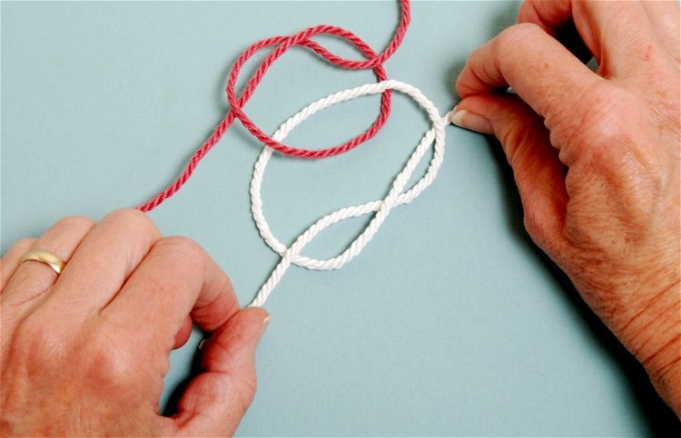 Image of Tie a second overhand knot with the white rope.