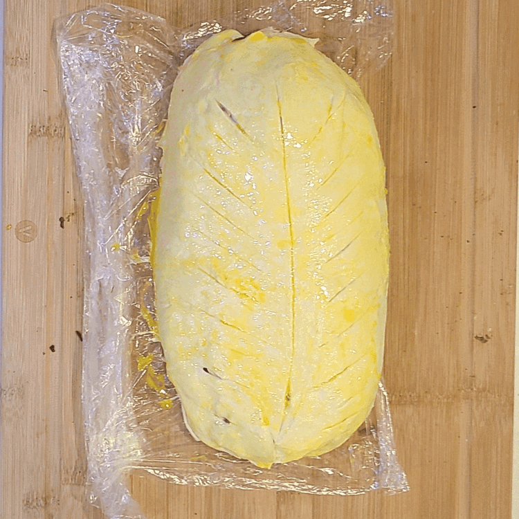 Image of Remove plastic wrap, then transfer the roll to a foil-lined baking sheet. Using a paring knife, score the top of the pastry in several places, brush with egg wash and sprinkle with flaky salt.