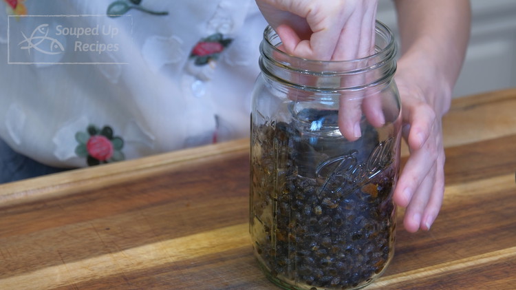 Image of Fill a small glass with 3 tbsp of high-alcohol-content liquor. Dig a small hole in the middle of the beans and carefully place the glass into the mason jar. Use a pair of chopsticks to compact the beans around the...