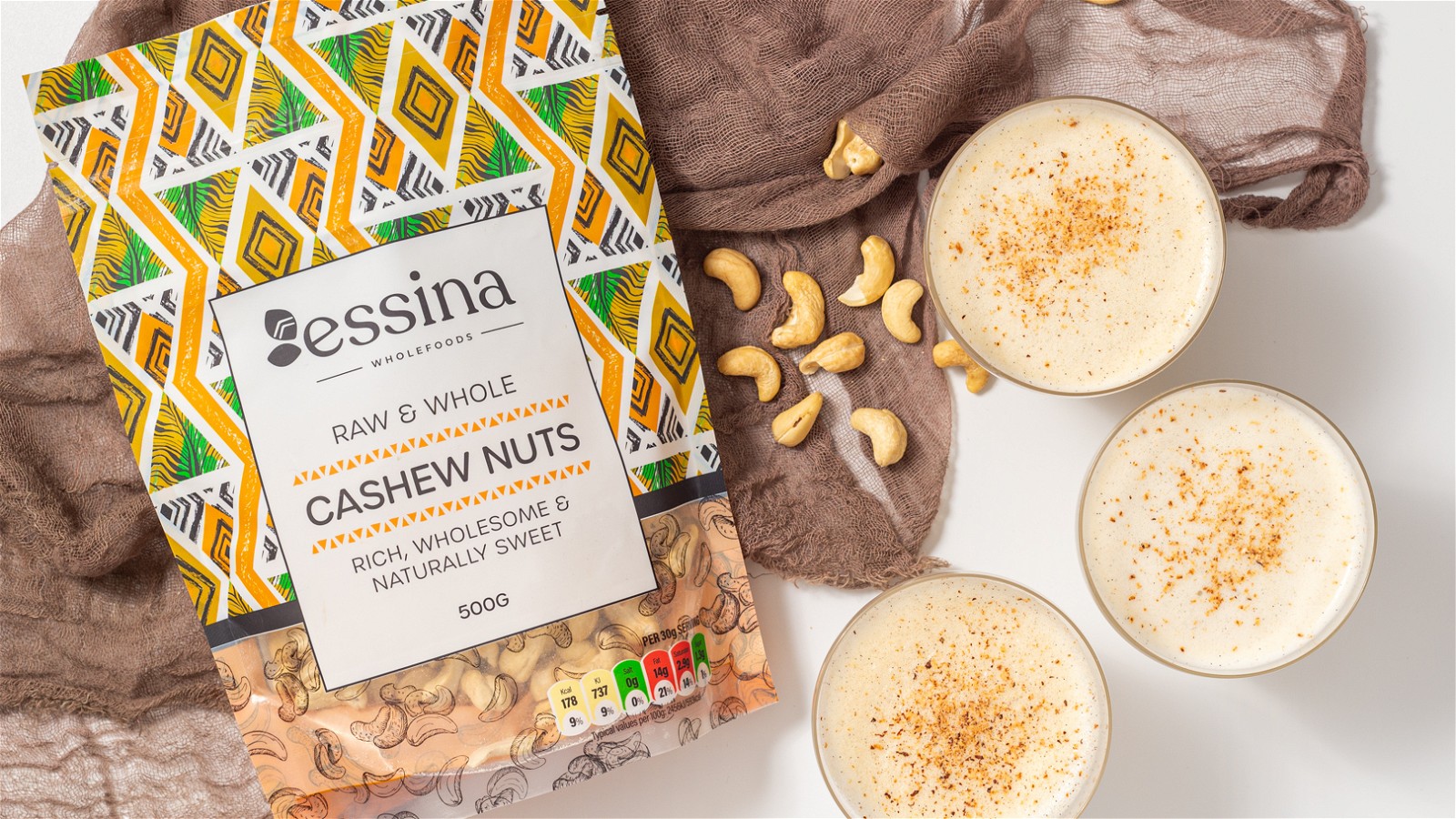 3 cups of vegan virgin eggnog image next to essina wholefoods cashew bag and some cashew nuts strewn on the table