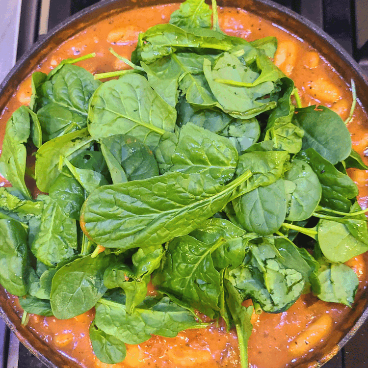 Image of After the initial 5 minutes, introduce the fresh spinach and cook on medium heat, stirring frequently, for about 5 minutes until the spinach wilts to your liking. If you prefer a thicker sauce, cook it for a longer duration.