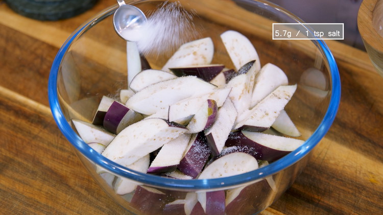 Image of Add the eggplant and 1 tsp of salt to a big mixing bowl and toss thoroughly. Set it aside for 15 minutes. Eggplant is a tricky vegetable. Without the correct preparation, it will taste extremely plain. The salt will soften...