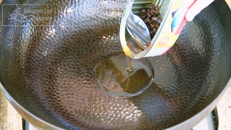 Image of Preheat your wok over a medium-heat stove. The fried dace is cured in oil, so you will have excess oil in the can. Add the oil to the wok and leave the fermented black beans behind.
