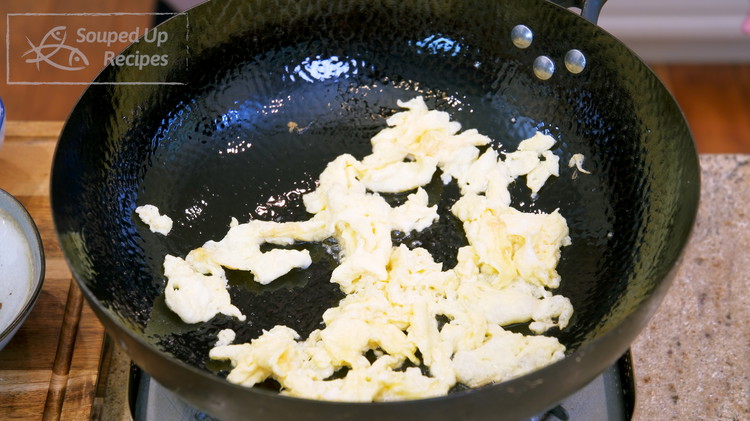 Image of Pour in the beaten egg. Stir for 40 - 50 seconds or until the egg is set. Break the egg into bite-size pieces. Turn off the heat. Remove the egg from the wok and set it aside.