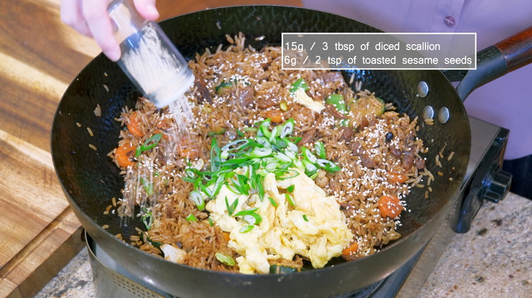 Image of When you see some rice grains dancing and jumping at the bottom of the wok, that is the sign that tells you your rice is fluffy and toasty; you can add the egg, diced scallion, and toasted sesame seeds. Toss...