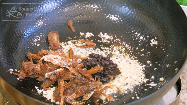 Image of Place the wok over a medium heat stove and add the oil from the can and 1 Tbsp minced garlic. Saute until fragrant. Add the fermented black beans and fried dace. Stir over medium-low heat for 1 minute.
