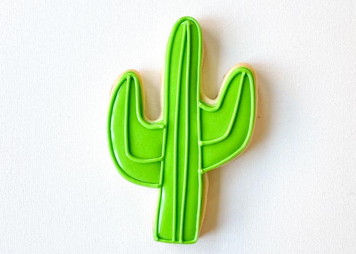 Image of Outline the shape and pipe one line on the other arm of the cactus using piping consistency green icing, following the contours as shown. A dry base equals greater definition between your flood and your piping consistency detail.