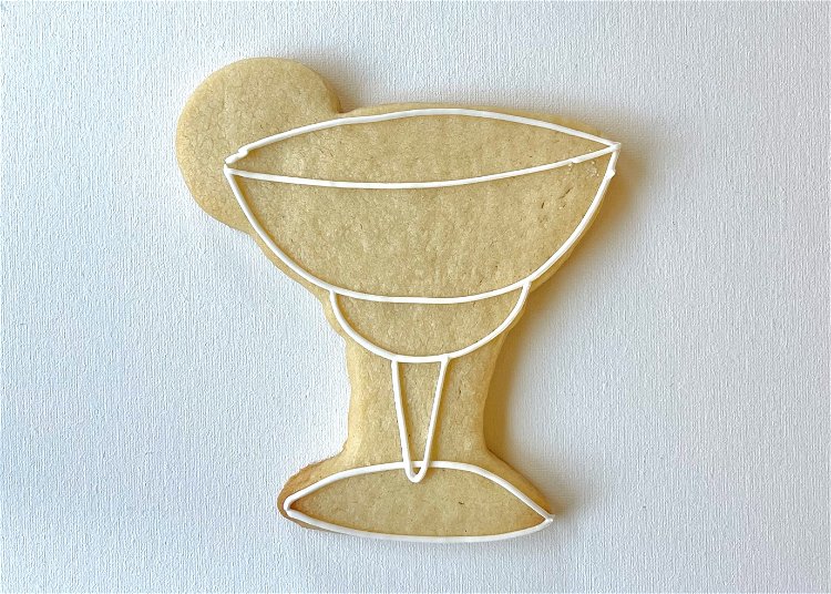 Image of Outline the margarita glass in white piping consistency icing, creating definition between the different parts as shown.