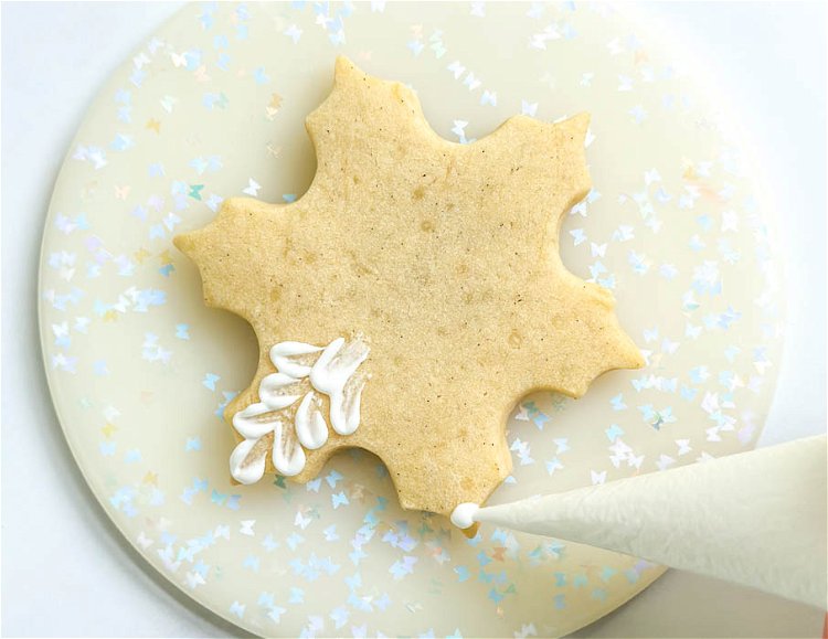 Image of Starting with the outer points of the snowflake, pipe a pea-sized dot of royal icing.