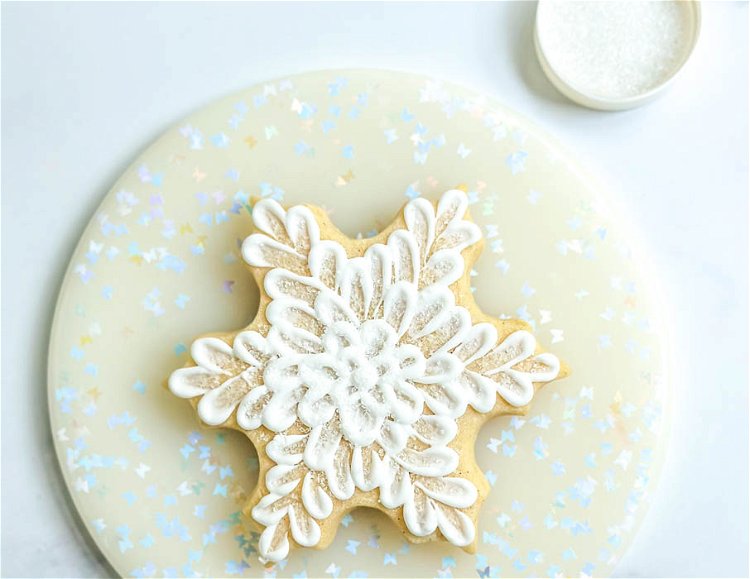 Image of Carefully transfer the cookie to a clean plate. Sprinkle the white sanding sugar all over the cookie. Now you can admire this beautiful edible snowflake! 