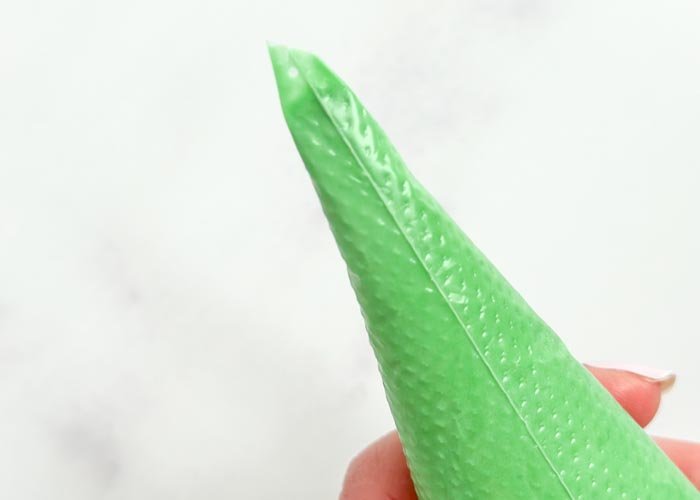 Image of Cut your green piping consistency icing bag on a 45 degree angle. Alternatively, you can use a petal shaped piping tip such as Wilton 102.