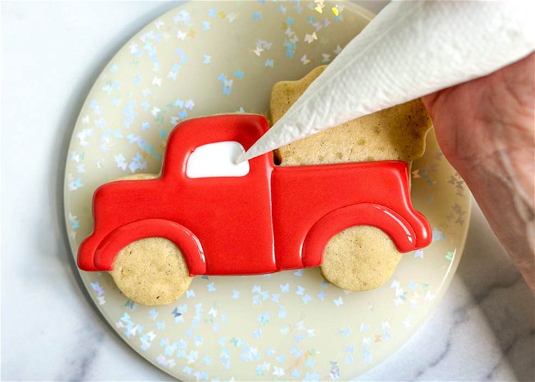 Image of Using the white flood consistency royal icing, fill in the truck's front window and smooth out the icing as needed with your scribe tool or toothpick.