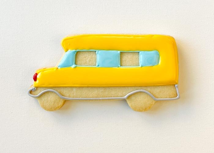 Image of Using flood consistency yellow icing, flood the yellow part of the bus. Let dry for 30-60 minutes, until crusting over. Once dry, begin flooding the windows. Flood every other window, as this gives the icing time to dry-therefore, it won't run.