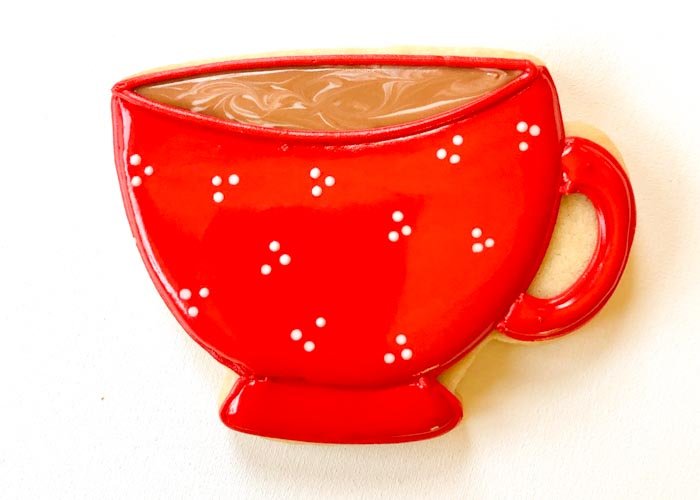 Image of Next, flood the main part of the teacup with red flood consistency icing. While the flood is still wet, pipe some white dots using your white flood consistency icing into the red flood. This wet-on-wet technique will allow the dots to blend into the red base flood. Wait for the main body of the teacup to dry until just crusting over. Again, you can speed up the process by placing your cookies near a fan. Once your red flood with white dots has crusted over, flood the handle and base of the teacup. 