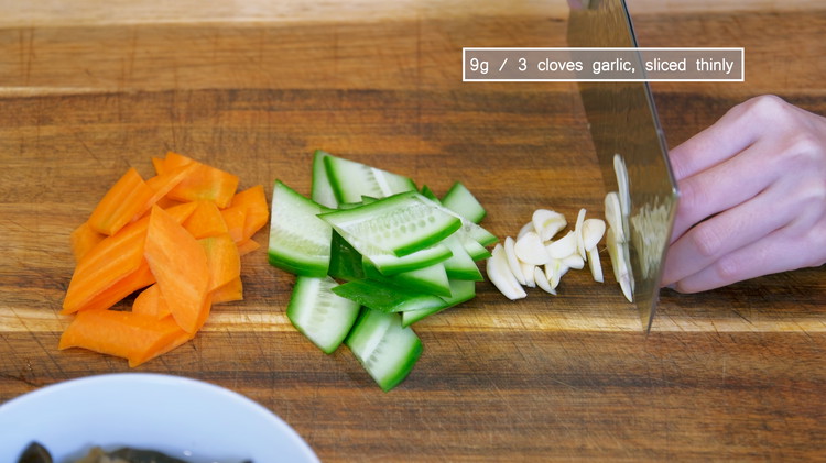 Image of Cut the carrot, cucumber, and garlic into thin slices. I do see lots of Chinese take out restaurants add napa cabbage to this dish, which doesn’t ruin the recipe but carrot and cucumber are more of the legit collocation.