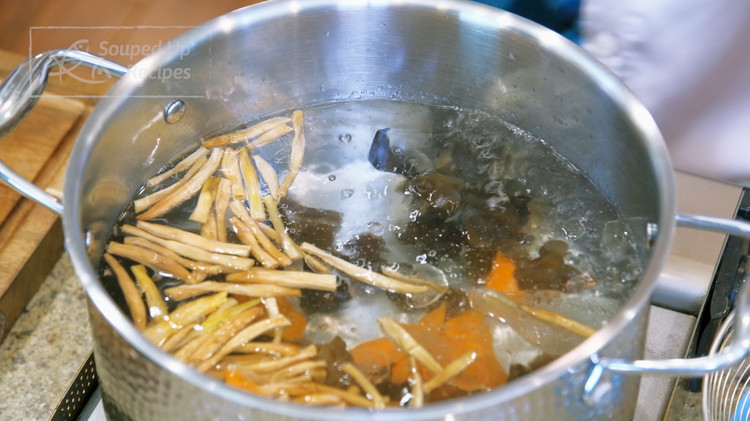 Image of Bring a pot of water to a boil. Add a big drizzle of oil, wood ear mushroom, daylily flowers, and carrot slices (reserve the cucumber on the side). Blanch the vegetables for 25 seconds. The oil will coat the surface...