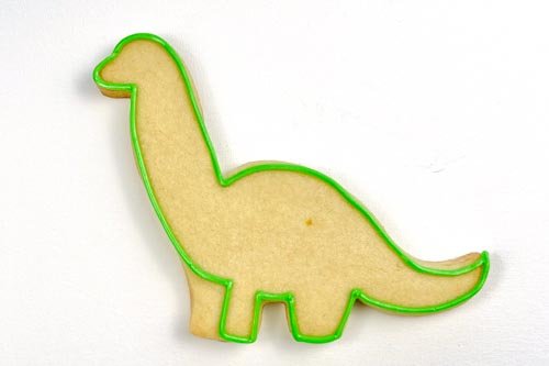 Image of Using piping consistency green icing, outline the shape. Be sure to define all 4 legs when outlining, as this will help to add dimension to your brontosaurus.