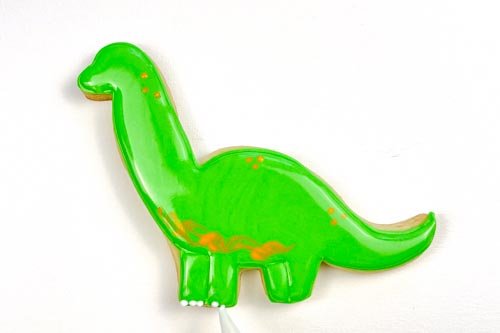 Image of Using white piping consistency royal icing, pipe dots to create dino toes.
