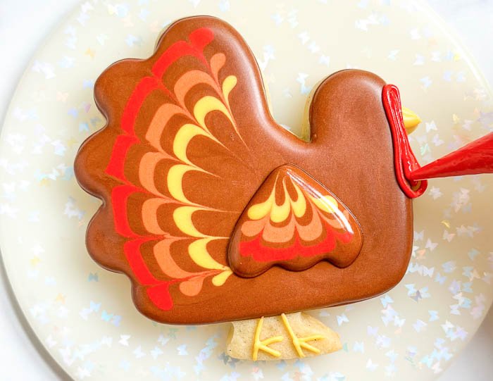 Image of Using the red detail consistency icing, pipe the turkey's snood.