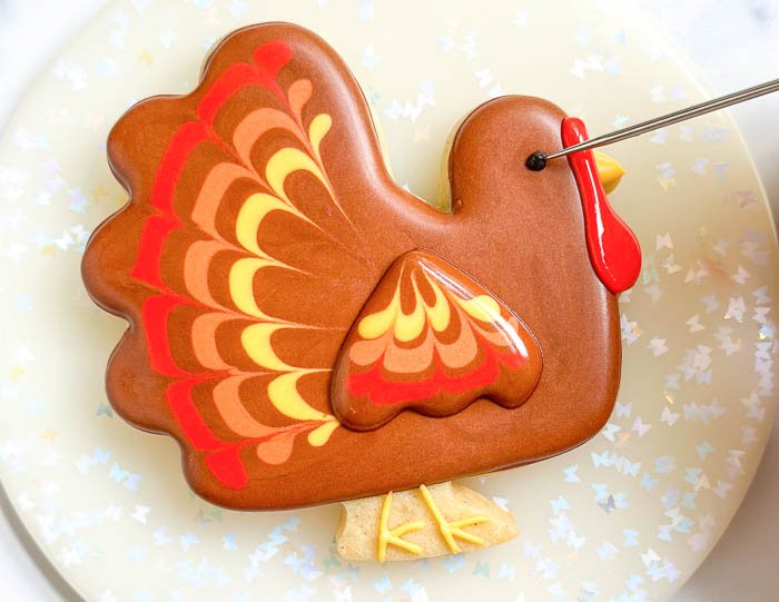 Image of Use your scribe tool or toothpick to smooth out the black icing you just piped. WATCH: How to Decorate a Colorful Turkey Cookie for Thanksgiving: 