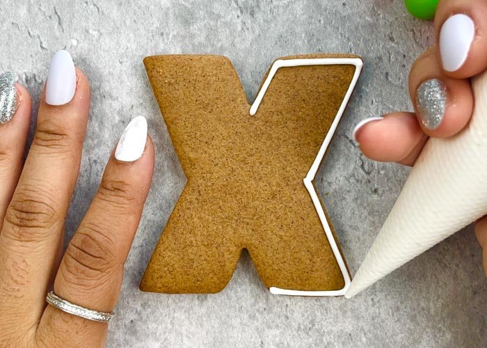Image of Using piping consistency white icing, outline the entire X shape as shown. 