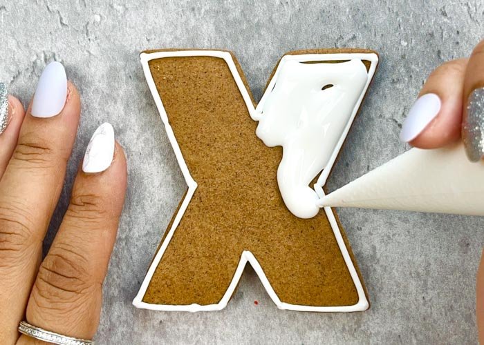 Image of With your piping consistency white icing, pipe a few squiggles in the body of the X shape. This will prevent your flood consistency icing from collapsing, or cratering.