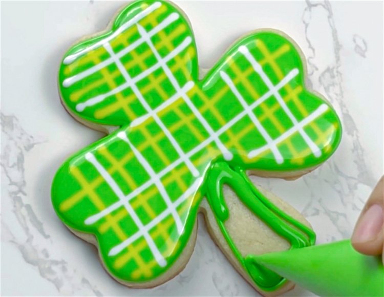 Image of Fill in the stem of your shamrock with green flood icing. Move quickly to the next step, as your base flood needs to be wet for the design.