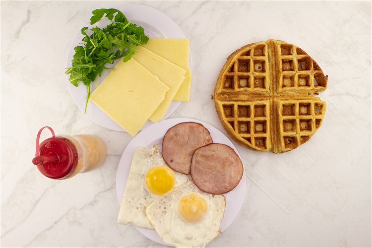 Image of Prepare your ingredients. Fry two eggs along with two pieces of Canadian bacon (you can also use sausage or bacon if you prefer). Make an Ann Clark Belgian Waffle.