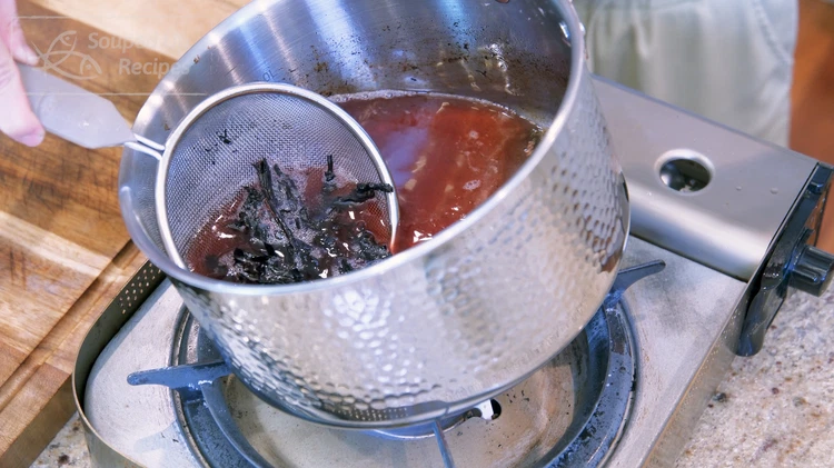Image of Optionally, tear the lithospermum root (紫草) into smaller pieces and add it to a sieve. Put it into the hot oil and stir for 20-30 seconds or until the oil turns into a reddish-purple color. Remove the lithospermum root from...