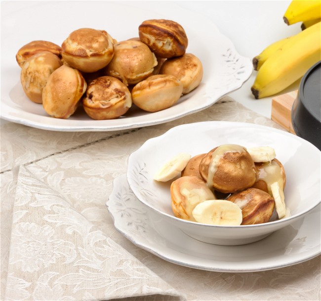 Two white bowls full of Banana Bread Donut Bites on a beige table cloth.