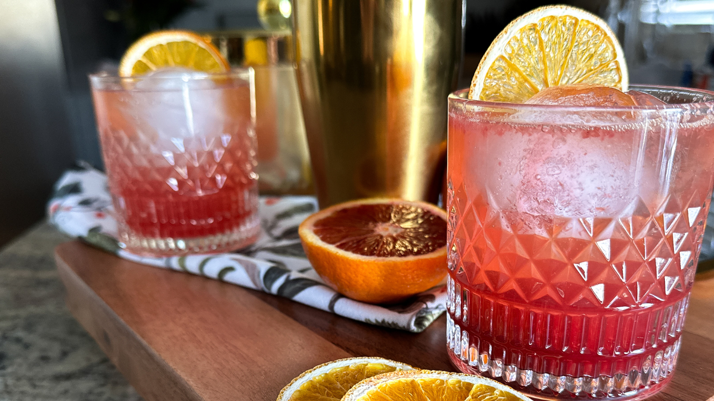 two pink mocktails topped with and surrounded by citrus